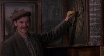 Movie still from “An American Werewolf in London” (1981), directed by John Landis – A man holding a banana in front of a chalkboard; Medium shot, Over the shoulder angle