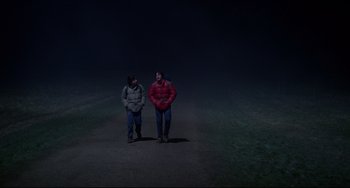 Movie still from “An American Werewolf in London” (1981), directed by John Landis – A couple of people that are standing in the dirt; Wide shot, High angle