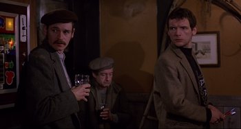 Movie still from “An American Werewolf in London” (1981), directed by John Landis – A group of men standing next to each other holding wine glasses; Medium shot, Over the shoulder angle