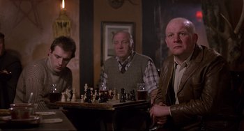 Movie still from “An American Werewolf in London” (1981), directed by John Landis – A group of men sitting at a table playing chess; Medium shot, Over the shoulder angle