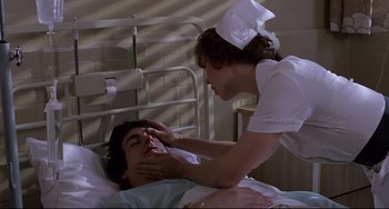Movie still from “An American Werewolf in London” (1981), directed by John Landis – A nurse touching the forehead of a patient in a hospital bed; Medium shot, High angle