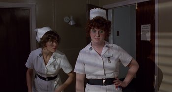 Movie still from “An American Werewolf in London” (1981), directed by John Landis – Two women dressed as nurses are standing in front of a mirror; Medium shot, Low angle