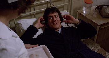 Movie still from “An American Werewolf in London” (1981), directed by John Landis – A man laying in a bed wearing headphones; Close Up shot, High angle