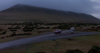 Movie still from “An American Werewolf in London” (1981), directed by John Landis – A car is driving down a road in the middle of nowhere at night; Extreme Wide shot, High angle