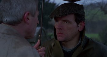 Movie still from “An American Werewolf in London” (1981), directed by John Landis – A man holding an umbrella over another man's face; Close Up shot, Over the shoulder angle