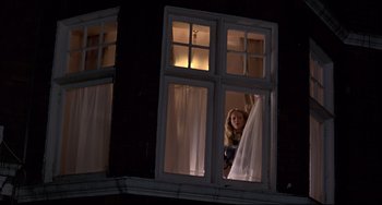 Movie still from “An American Werewolf in London” (1981), directed by John Landis – A woman looking out of a window at night; Wide shot, Low angle