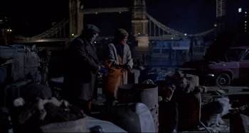 Movie still from “An American Werewolf in London” (1981), directed by John Landis – Two men standing next to each other near a pile of trash; Wide shot, High angle