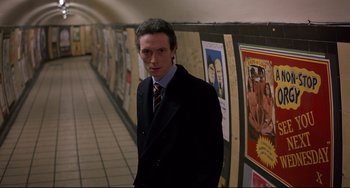 Movie still from “An American Werewolf in London” (1981), directed by John Landis – A man in a suit standing in front of posters; Medium shot, Low angle