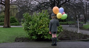Movie still from “An American Werewolf in London” (1981), directed by John Landis – A little girl holding balloons in front of a bush; Wide shot, Low angle