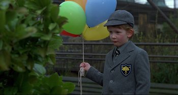 Movie still from “An American Werewolf in London” (1981), directed by John Landis – A young boy holding a bunch of colorful balloons; Medium shot, Low angle
