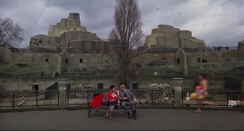 Movie still from “An American Werewolf in London” (1981), directed by John Landis – A man and a woman sitting on top of a park bench; Wide shot, High angle