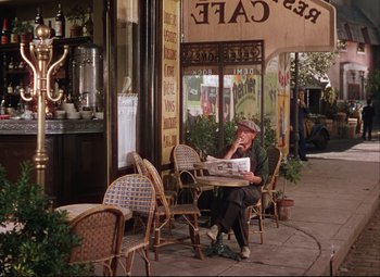 Movie still from “An American in Paris” (1951), directed by Vincente Minnelli – A woman sitting at a table outside of a restaurant; Wide shot, High angle