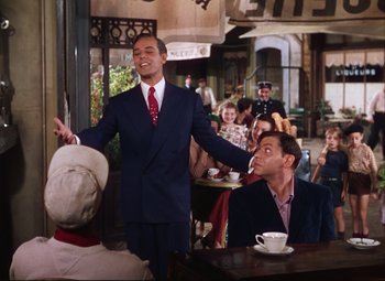 Movie still from “An American in Paris” (1951), directed by Vincente Minnelli – A man in a suit and tie standing in front of a crowd; Medium shot, High angle