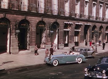 Movie still from “An American in Paris” (1951), directed by Vincente Minnelli – A car parked on the side of the road near a building; Extreme Wide shot, High angle