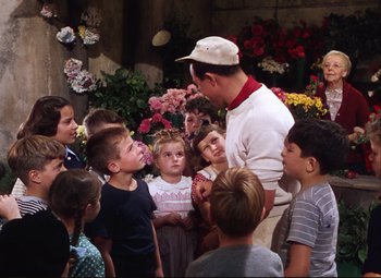 Movie still from “An American in Paris” (1951), directed by Vincente Minnelli – A group of children gathered around a man in a white shirt; Medium shot, Over the shoulder angle