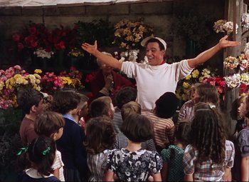 Movie still from “An American in Paris” (1951), directed by Vincente Minnelli – A group of people standing around a crowd of children; Medium shot, High angle