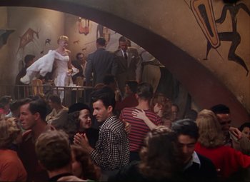 Movie still from “An American in Paris” (1951), directed by Vincente Minnelli – A group of people gathered in a room; Wide shot, High angle