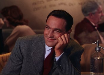Movie still from “An American in Paris” (1951), directed by Vincente Minnelli – A man wearing a suit and tie smiling for the camera; Close Up shot, Low angle