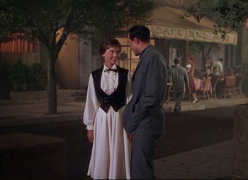 Movie still from “An American in Paris” (1951), directed by Vincente Minnelli – A man and a woman standing next to each other on the sidewalk; Medium shot, Over the shoulder angle