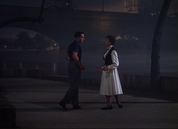 Movie still from “An American in Paris” (1951), directed by Vincente Minnelli – A man and a woman are talking to each other; Wide shot, Over the shoulder angle