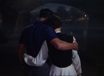 Movie still from “An American in Paris” (1951), directed by Vincente Minnelli – A man and a woman hugging each other in the dark; Medium shot, High angle