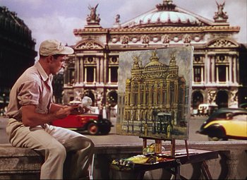 Movie still from “An American in Paris” (1951), directed by Vincente Minnelli – A man sitting in front of an easel painting a picture; Wide shot, Low angle
