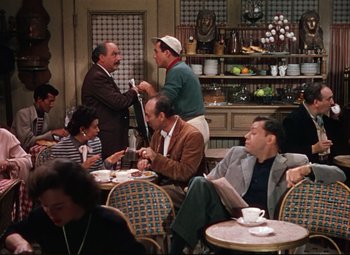 Movie still from “An American in Paris” (1951), directed by Vincente Minnelli – A group of people sitting at a table in a restaurant; Wide shot, High angle