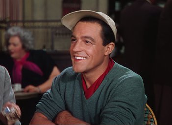 Movie still from “An American in Paris” (1951), directed by Vincente Minnelli – A man wearing a baseball hat and smiling; Medium shot, Over the shoulder angle