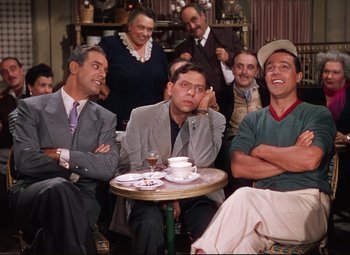 Movie still from “An American in Paris” (1951), directed by Vincente Minnelli – A group of men sitting at a table with a drink; Medium shot, High angle