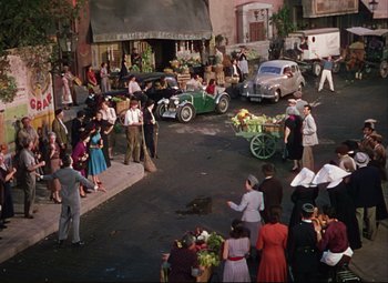 Movie still from “An American in Paris” (1951), directed by Vincente Minnelli – A crowd of people standing on the side of the street; Extreme Wide shot, High angle
