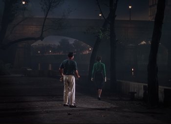 Movie still from “An American in Paris” (1951), directed by Vincente Minnelli – A man and a woman are walking in the dark; Wide shot, High angle