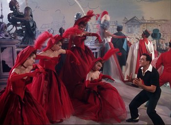 Movie still from “An American in Paris” (1951), directed by Vincente Minnelli – A group of women in red dresses dancing in front of an audience; Wide shot, Low angle