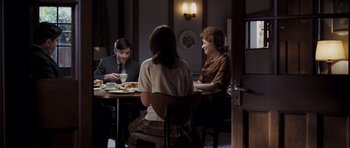Movie still from “An Education” (2009), directed by Lone Scherfig – A group of people sitting at a table with plates of food on it; Medium shot, Over the shoulder angle