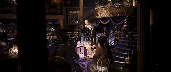 Movie still from “An Education” (2009), directed by Lone Scherfig – A group of people sitting at a table in front of a staircase; Wide shot, High angle