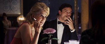 Movie still from “An Education” (2009), directed by Lone Scherfig – A man and a woman sitting at a dinner table smoking cigarettes; Medium shot, Low angle
