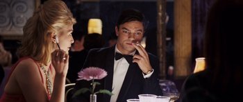 Movie still from “An Education” (2009), directed by Lone Scherfig – A man in a tuxedo sitting in front of a flower; Medium shot, Over the shoulder angle