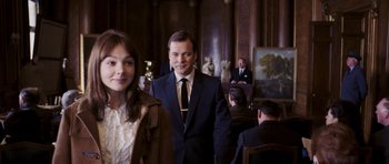 Movie still from “An Education” (2009), directed by Lone Scherfig – A man and a woman in suits in a room; Medium shot, Over the shoulder angle