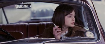 Movie still from “An Education” (2009), directed by Lone Scherfig – A woman sitting in the back seat of a car smoking a cigarette; Close Up shot, Over the shoulder angle