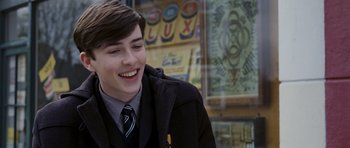 Movie still from “An Education” (2009), directed by Lone Scherfig – A young man in a suit and tie smiling; Close Up shot, Over the shoulder angle