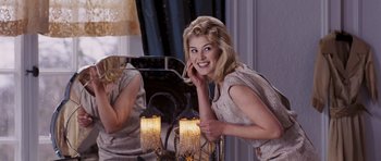Movie still from “An Education” (2009), directed by Lone Scherfig – A beautiful young blond haired woman posing in front of a mirror; Medium shot, Over the shoulder angle