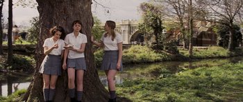 Movie still from “An Education” (2009), directed by Lone Scherfig – Two young women standing next to a tree near a body of water; Wide shot, High angle