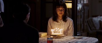 Movie still from “An Education” (2009), directed by Lone Scherfig – A woman sitting at a table with a cake with candles on it; Medium shot, Over the shoulder angle