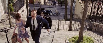 Movie still from “An Education” (2009), directed by Lone Scherfig – A man in a suit and tie running down a sidewalk; Wide shot, High angle