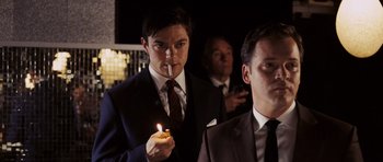 Movie still from “An Education” (2009), directed by Lone Scherfig – A man in a suit holding a lit candle in his hand; Medium shot, Over the shoulder angle