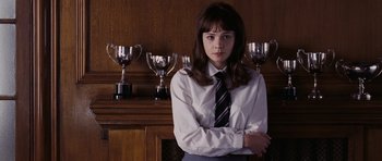 Movie still from “An Education” (2009), directed by Lone Scherfig – A girl in a dress shirt and tie standing in front of trophies; Medium shot, Low angle