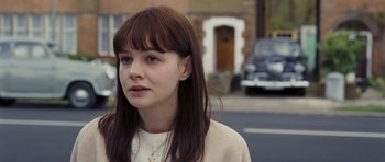 Movie still from “An Education” (2009), directed by Lone Scherfig – A woman with long brown hair wearing a white sweater; Close Up shot, Over the shoulder angle