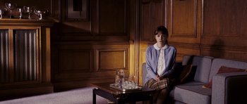 Movie still from “An Education” (2009), directed by Lone Scherfig – A woman sitting on a chair next to a coffee table; Wide shot, Over the shoulder angle