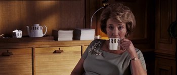 Movie still from “An Education” (2009), directed by Lone Scherfig – A woman sitting in a chair holding a cup of coffee; Medium shot, Over the shoulder angle