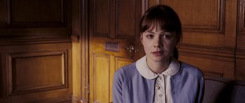 Movie still from “An Education” (2009), directed by Lone Scherfig – A young woman in a blue dress is standing in front of a wooden door; Close Up shot, Over the shoulder angle