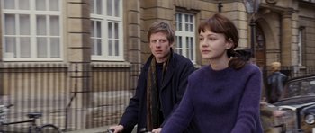 Movie still from “An Education” (2009), directed by Lone Scherfig – A man and a woman riding a bike down a street; Medium shot, Over the shoulder angle